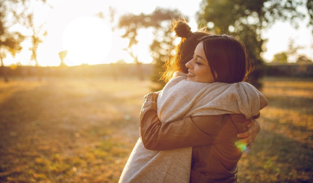 Two friends hugging after finding out one of them has been diagnosed with IBS