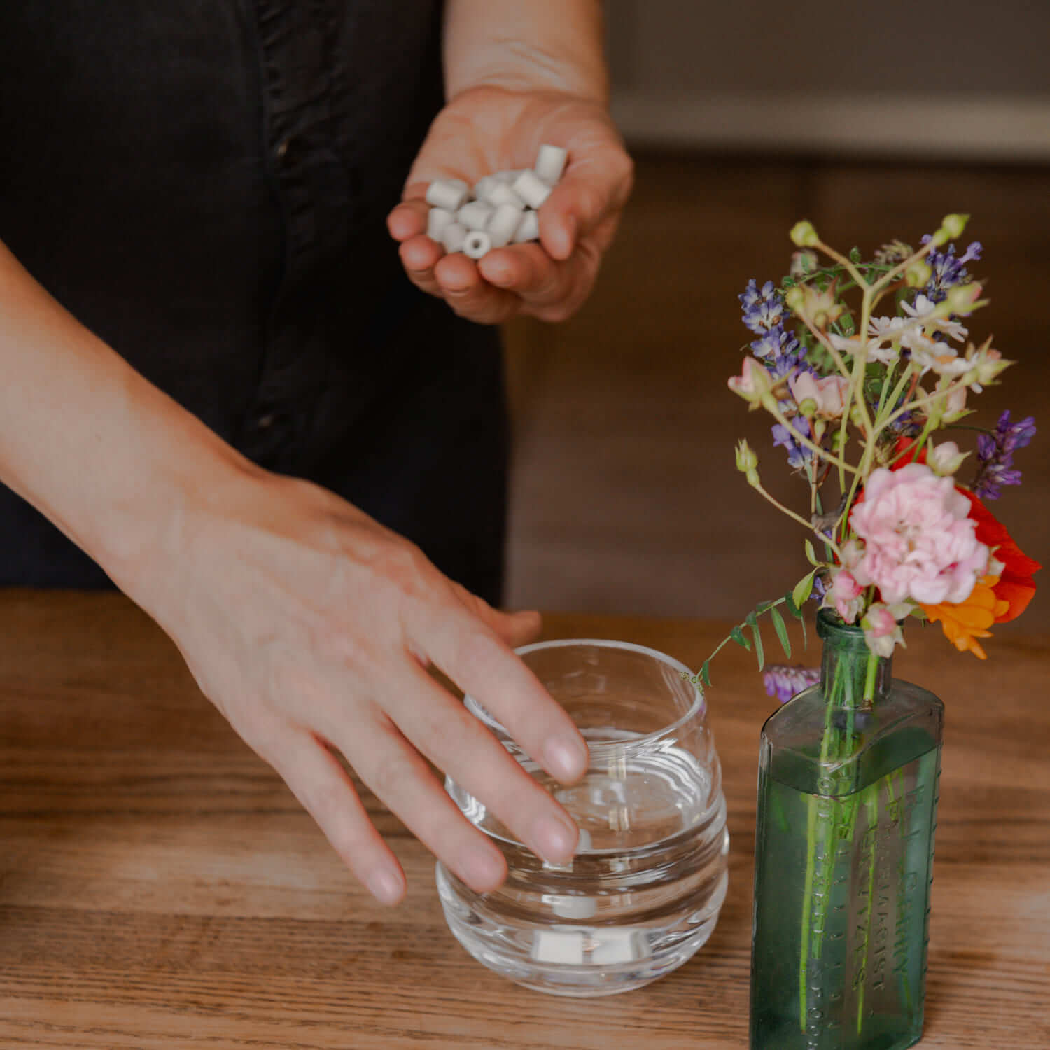 Women holding a glass of water and a handful of microbz ceramic water beads
