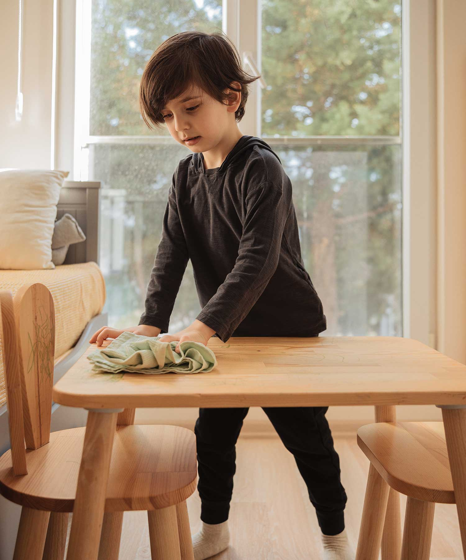 young boy cleaing a table with a cloth that has been sprayed with microbz cleaning probiotics