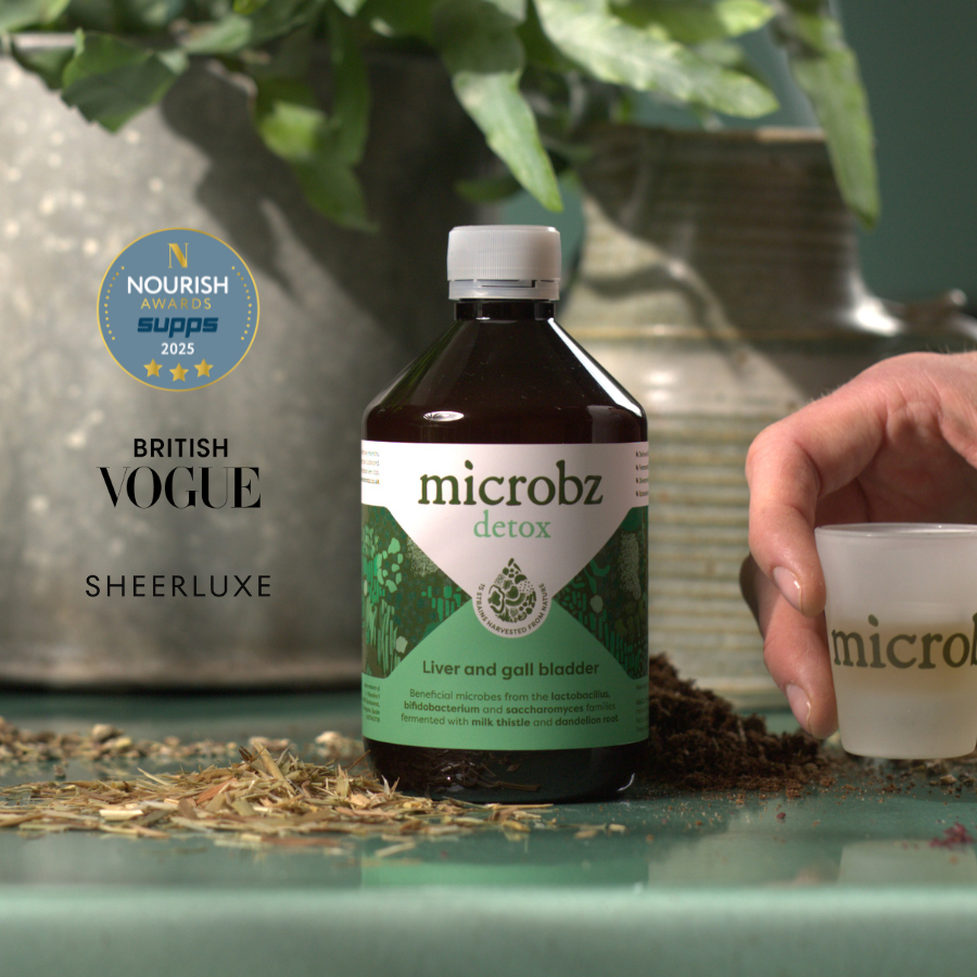 Bottle of microbz detox with a cup on a table with decorative elements