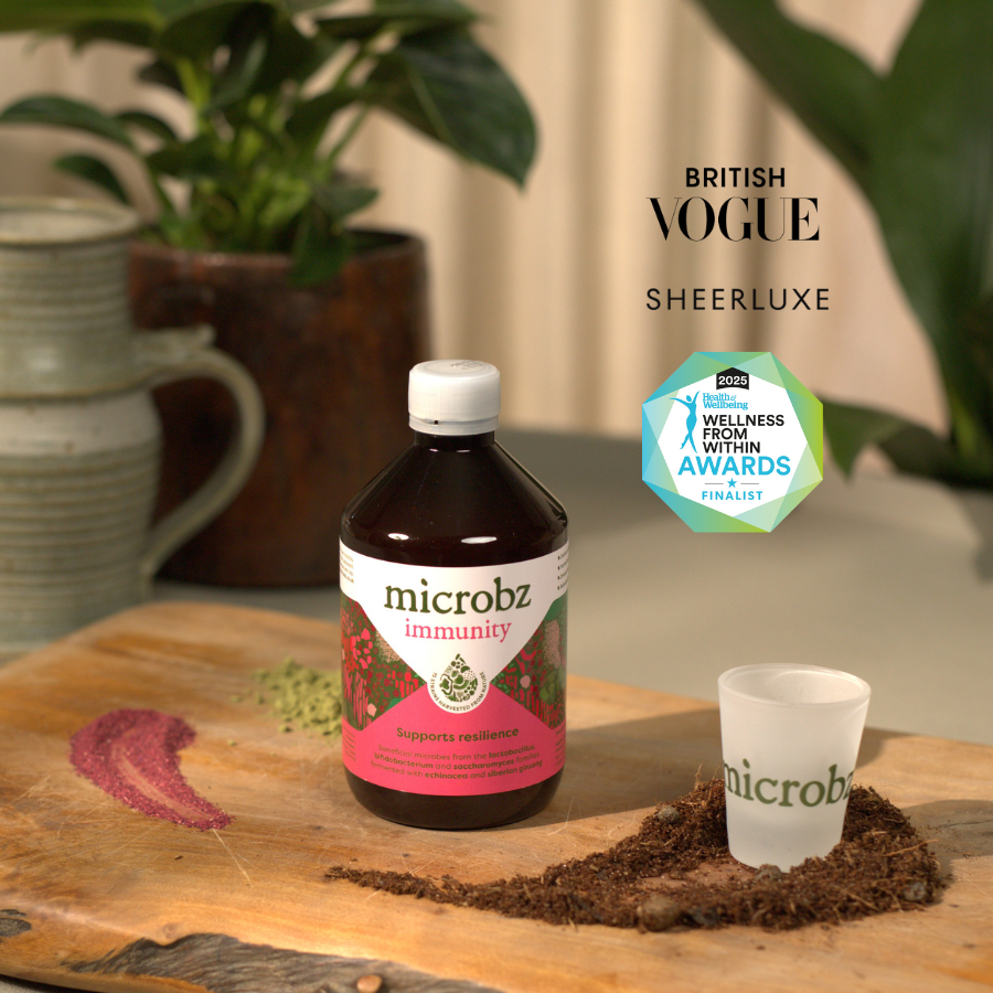 microbz immunity supplement bottle on a wooden surface with 'British Vogue Sheerluxe' and 'Wellness Food & Drink Within Awards' logos.