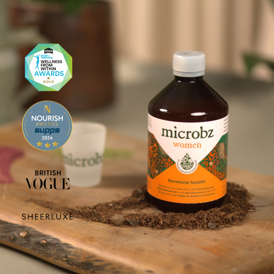Bottle of microbz women supplement on a wooden surface with awards logos displayed.