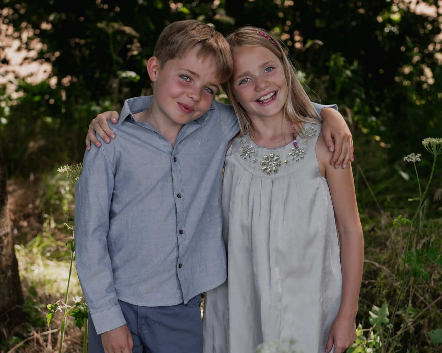 two young children with their arms around each others shoulders in a field