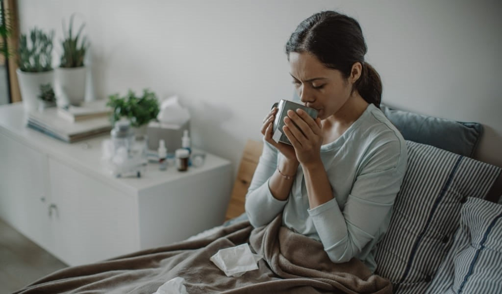 A woman in bed sick after getting a virus and taking antibiotics which can contribute to antimicrobial resistance