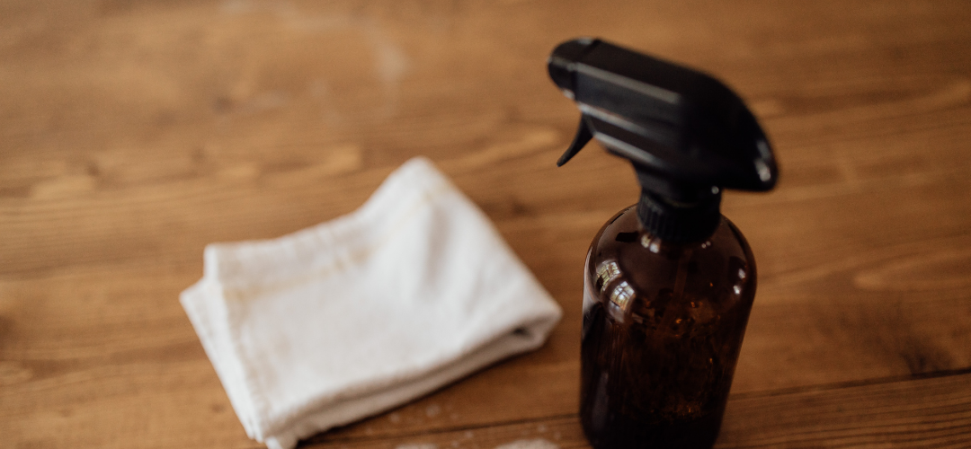 an image of a cleaning cloth on a wooden table and a glass bottle
