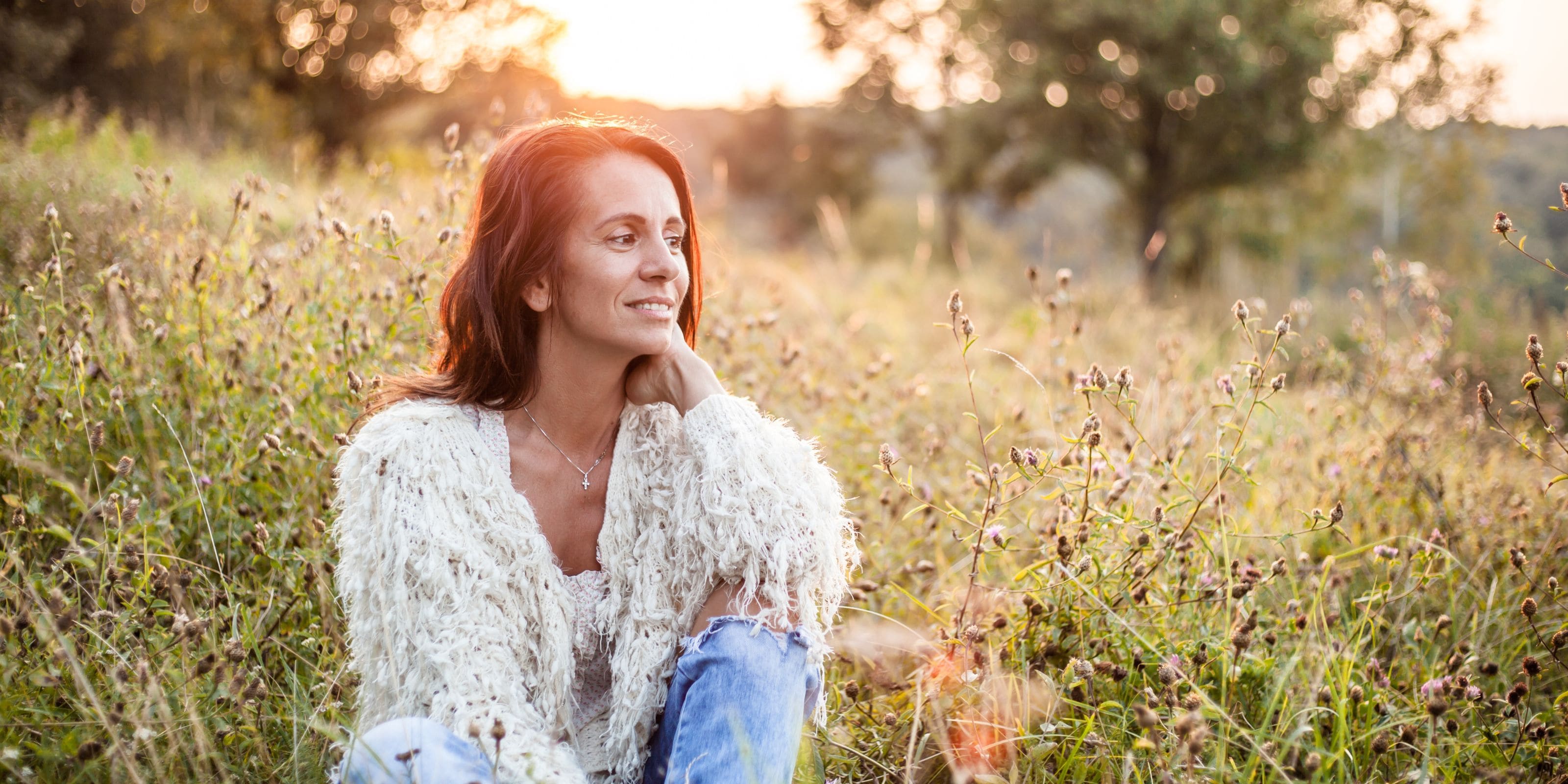 A woman in a field with the sunset thinking How to improve gut health to help alleviate menopause and perimenopause symptoms