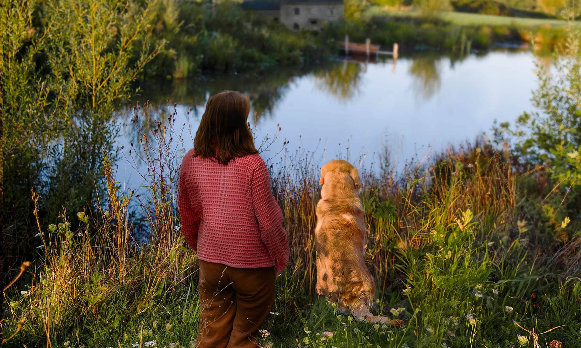Katie Allen and Kit the dog standing in the spirthill field over looking the pond