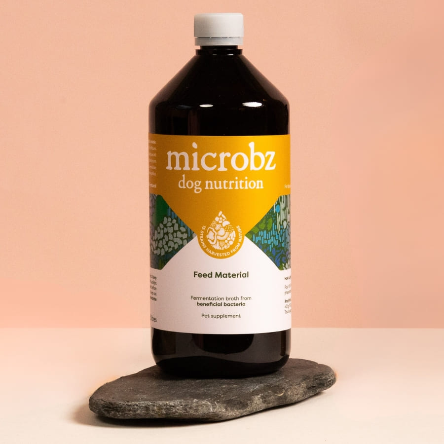 Bottle of microbz dog nutrition on a stone surface with a pink gradient background