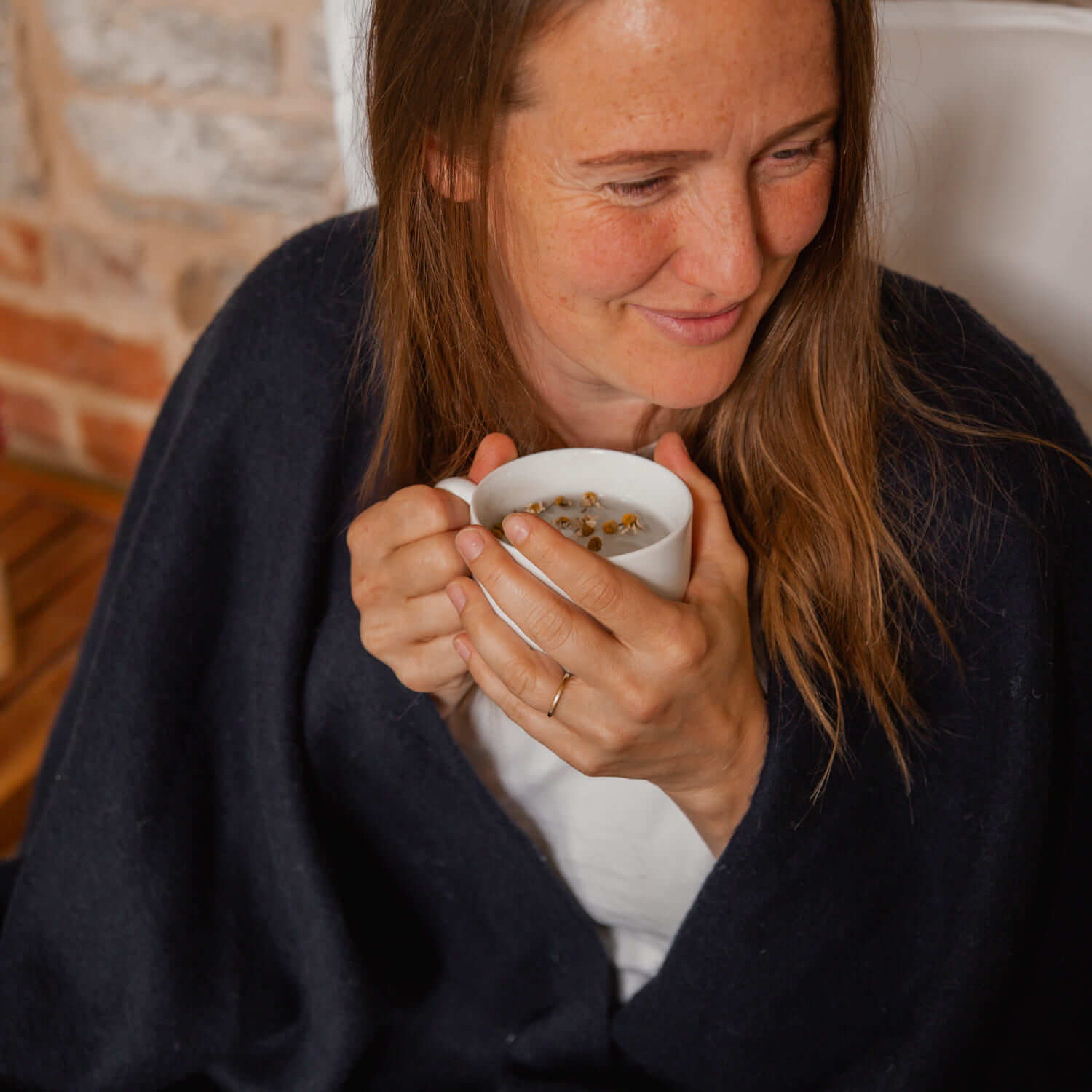 Katie Allen in a blanket holding a cup of chamomile tea with immunity probiotic