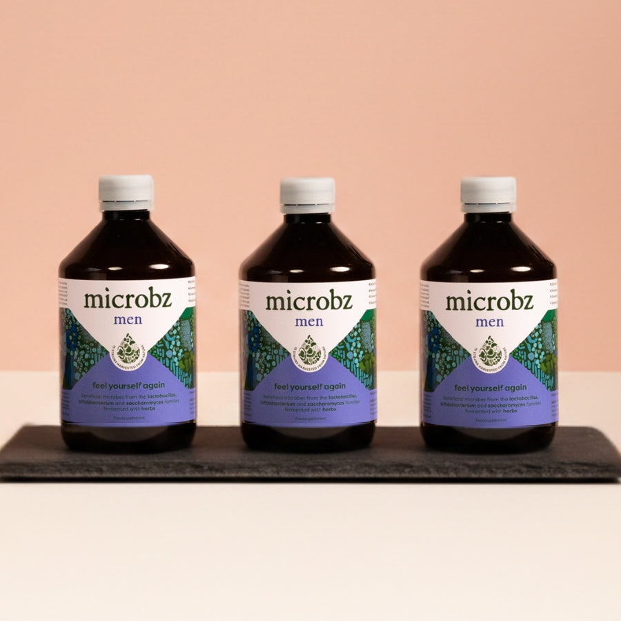 Three bottles of microbz men on a black tray with a beige background