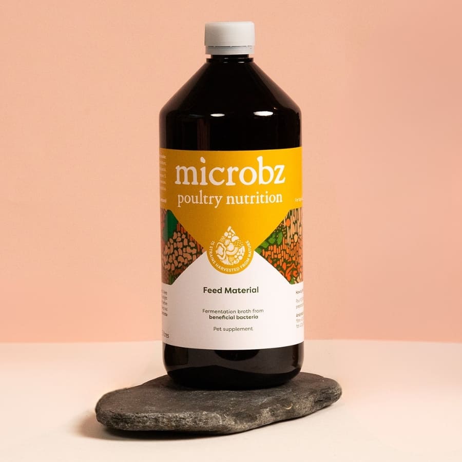 Bottle of microbz poultry nutrition feed material on a stone surface with a peach background