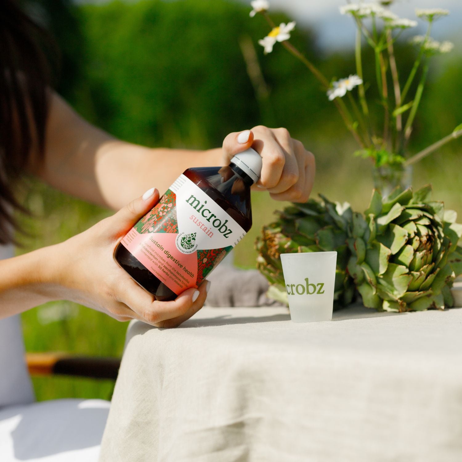 A woman holding a bottle of microbz sustain twisting the cap to open it.
